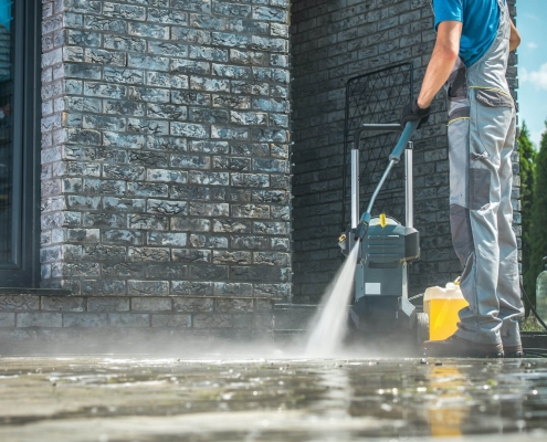 man pressure washing outdoor pavers